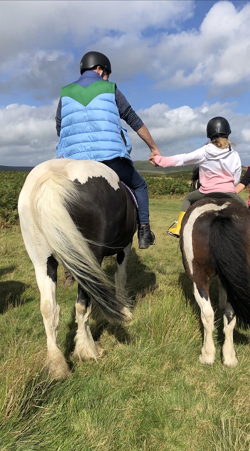Holding hands whilst horse riding in countryside
